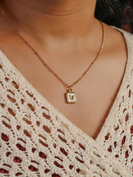 Ashborne Manasi white-enamel butterfly tag pendant on beaded satellite chain, worn on model