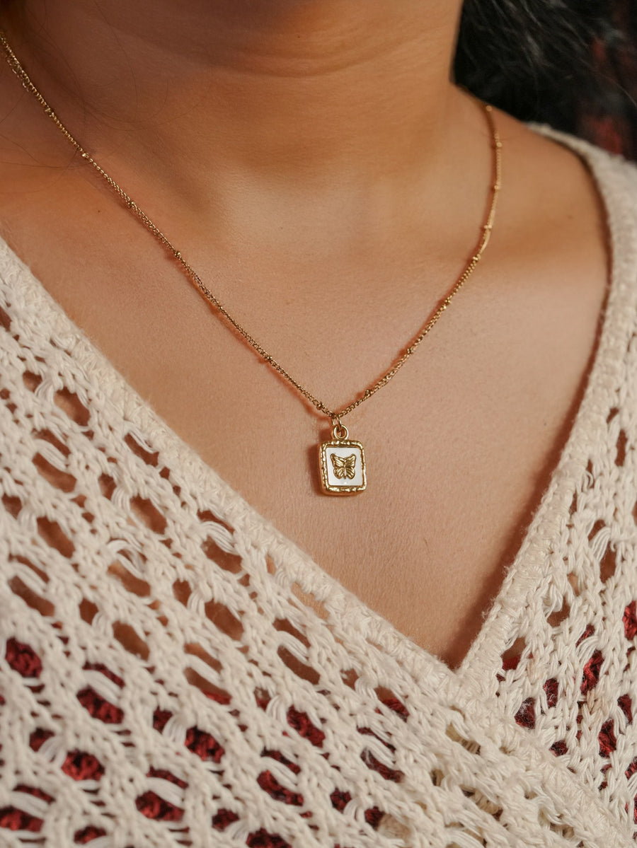 Ashborne Manasi white-enamel butterfly tag pendant on beaded satellite chain, worn on model