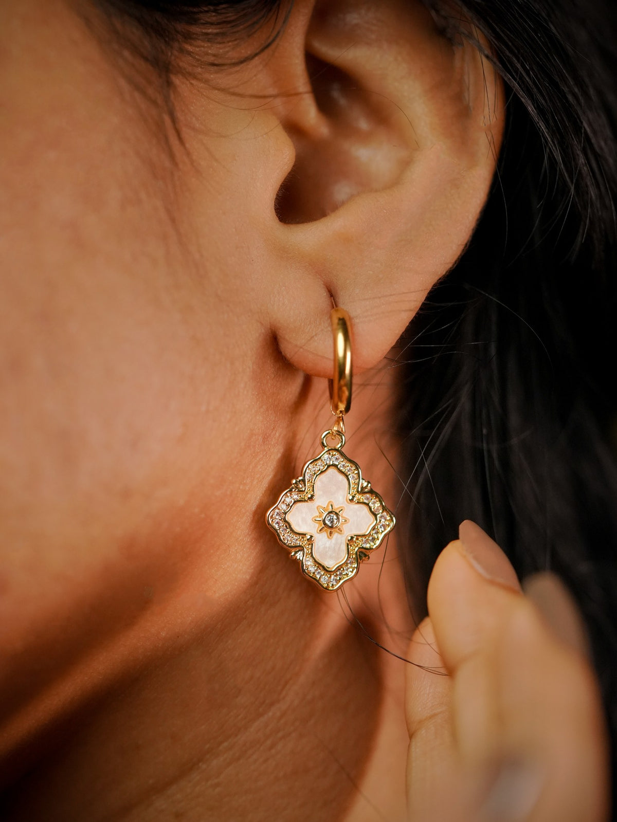 Ashborne Ishani clover huggie earring worn on the ear, mother-of-pearl drop detail