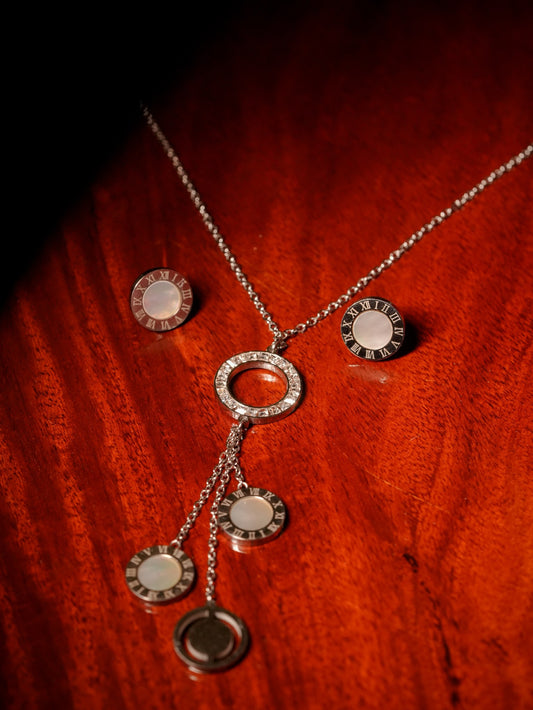 Ashborne Gayatri silver-tone roman-numeral coin necklace and stud set on wood
