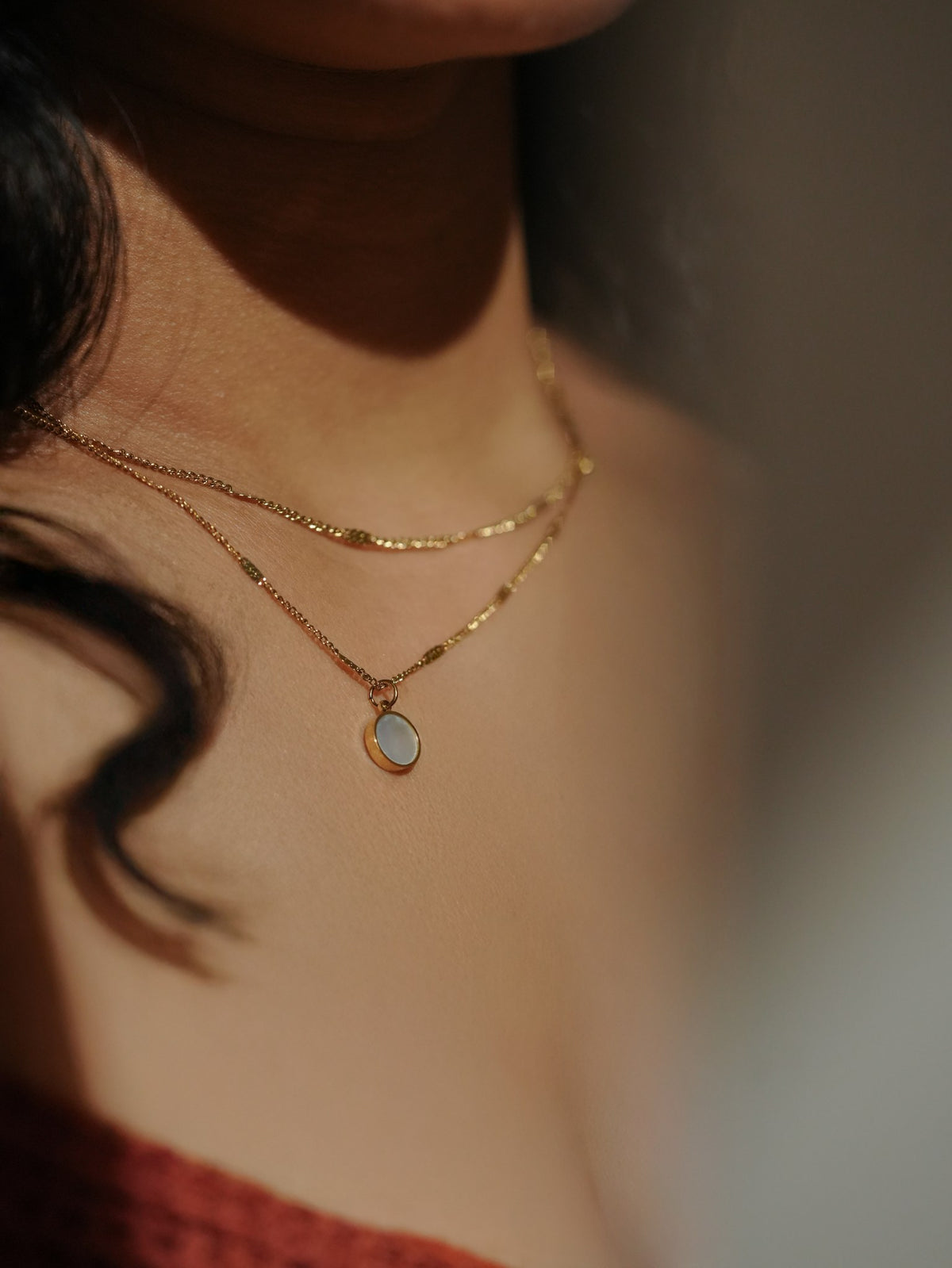 Ashborne Khushi round mother-of-pearl pendant on layered gold chains, worn