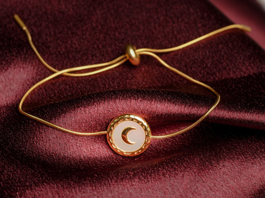 Ashborne Mishka crescent moon bracelet with adjustable slider clasp on maroon satin