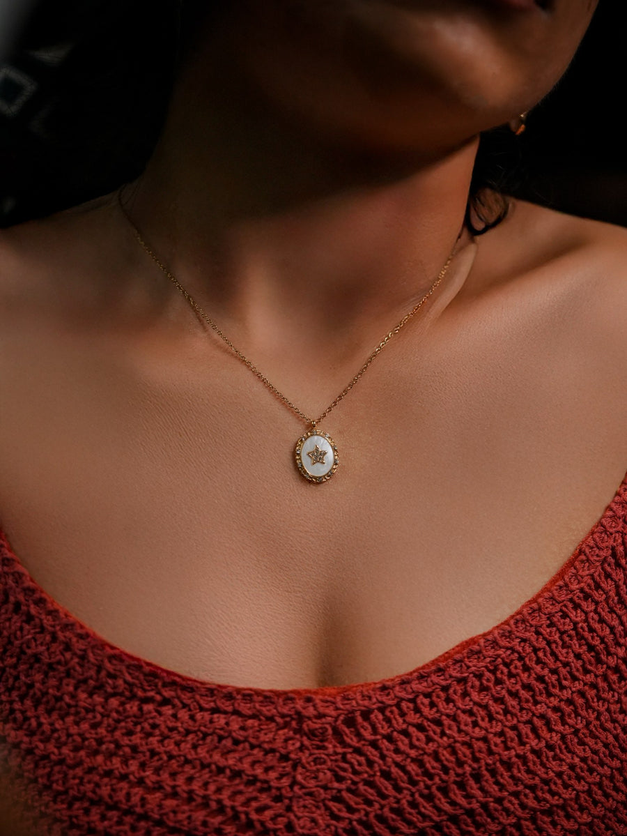 Ashborne Kavya oval mother-of-pearl pendant with beaded rim and crystal star, worn on model
